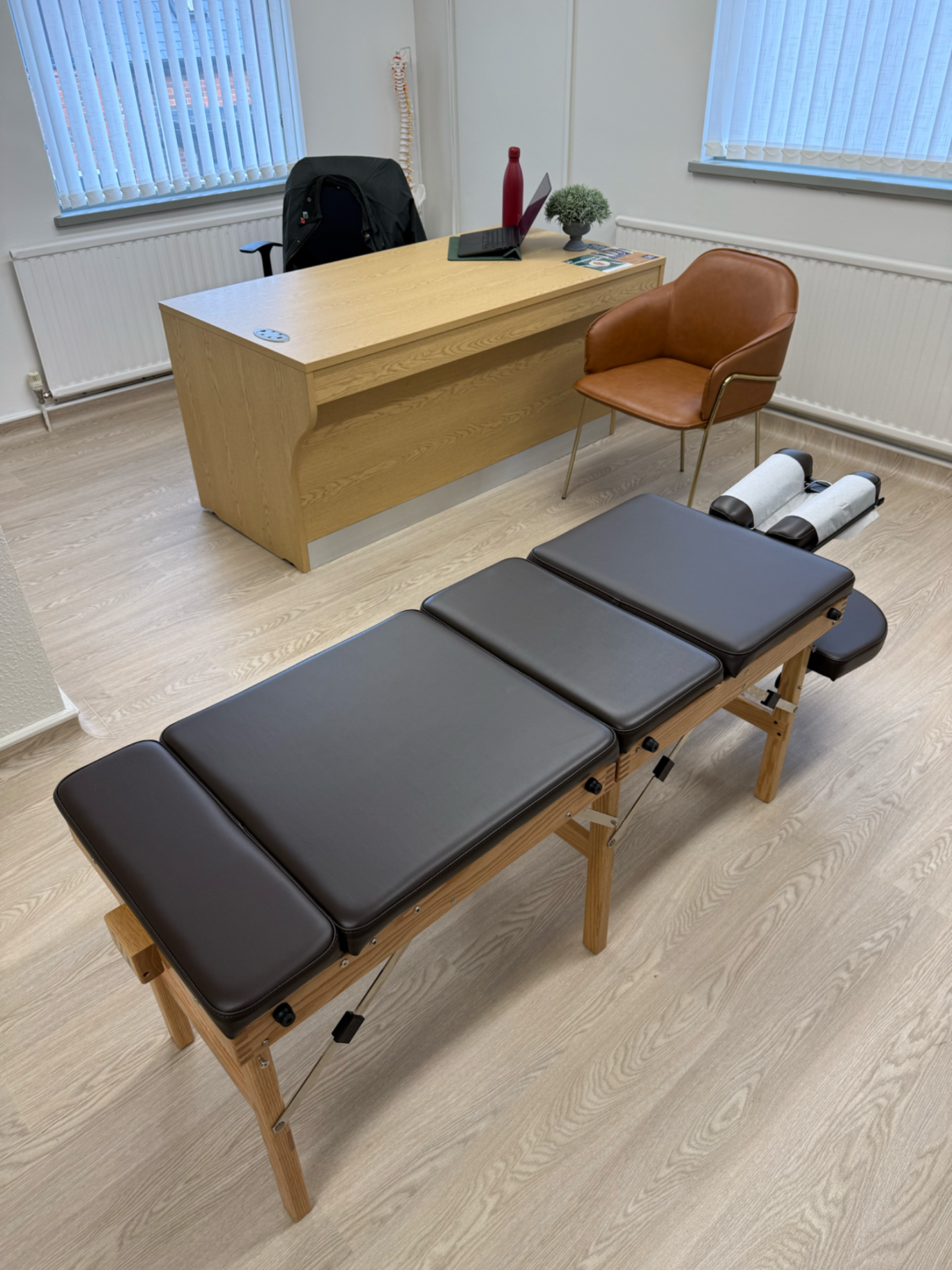 BU Chiropractic treatment room Alresford. With a espresso coloured chiropractic bench and desk with consultation chair.